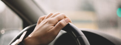 female driver with one hand on steering wheel